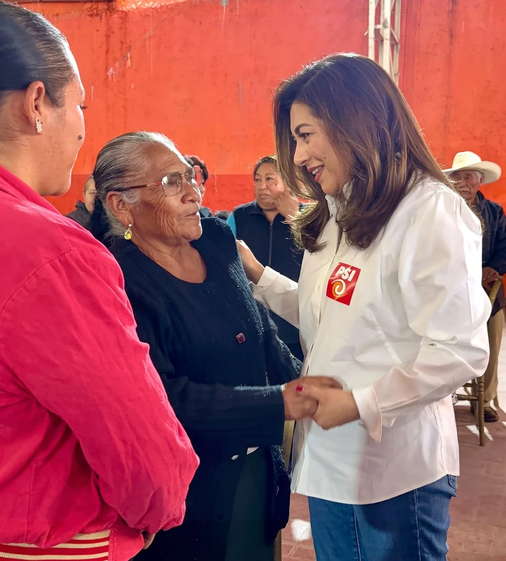 Nadia Navarro Acevedo saludando a una asistente durante el evento del PSI en Tlacotepec de Benito Juárez